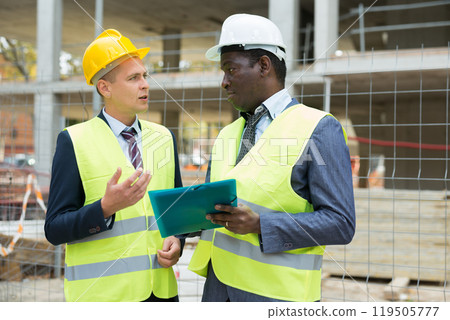 Engineer and architect discusses construction plan at construction site outdoor Engineer and architect discusses construction plan at construction site outdoor 119505777
