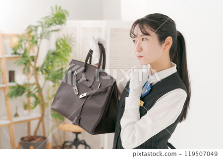 A female staff member appraising a used bag 119507049
