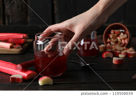 Rhubarb jelly in a jar with fresh rhubarb stems on a dark background 119508039