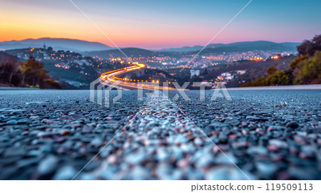 Empty asphalt road stretches straight ahead, leading towards the gleaming skyline 119509113
