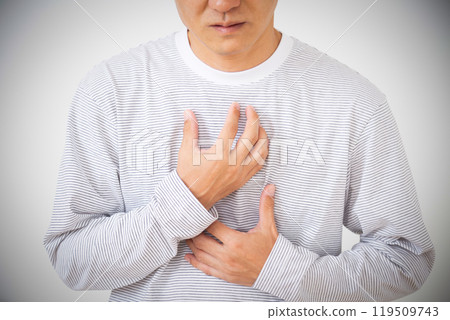 Middle-aged man suffering from chest pain holding his chest Middle-aged man suffering from chest pain holding his chest 119509743