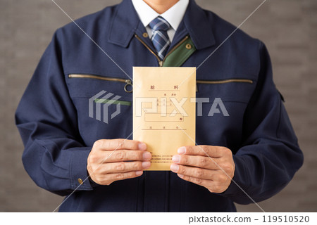 Middle-aged male businessman wearing work clothes holding a pay envelope 119510520
