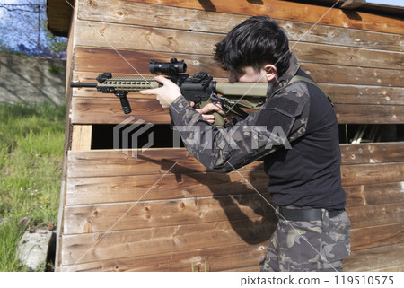 a young soldier stationed behind a shed 119510575