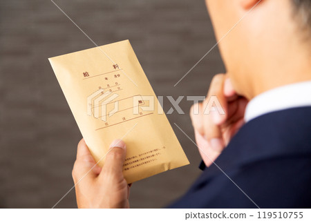 A middle-aged male businessman wearing work clothes worried about his pay packet 119510755