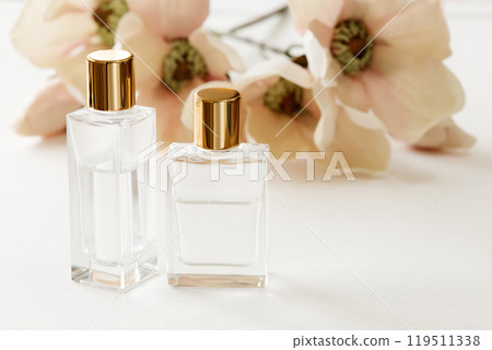 Two glass cosmetic bottles with gold caps and flowers 119511338