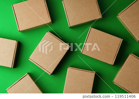 Brown cardboard boxes arranged on a vibrant green surface 119511406