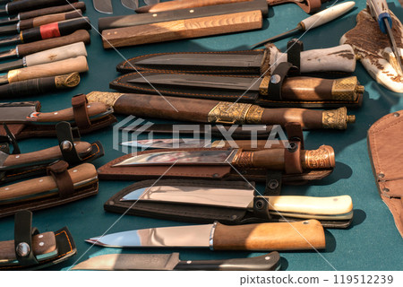Knives on the counter of a craftsman. Sale of knives. A large selection of knives of different shapes and sizes. Knives on the counter of a craftsman. Sale of knives. A large selection of knives of different shapes and sizes. 119512239