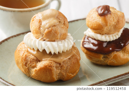 Religieuse French choux pastry dessert filled with custard closeup on the plate. Horizontal Religieuse French choux pastry dessert filled with custard closeup on the plate. Horizontal 119512458