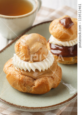 French Religieuse pastry profiteroles with custard cream and chocolate and coffee glaze close-up in a bowl. Vertical 119512461
