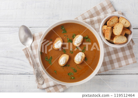 Homemade Soupe de poisson thick and hearty soup has a delicate flavor with a gentle fish undertone with croutons and aioli sauce closeup on the bowl. Horizontal top view 119512464