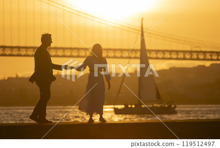 Couple holding hands and dancing by river at sunset Couple holding hands and dancing by river at sunset 119512497