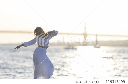 Woman dancing on the beach at sunset with golden gate bridge in background 119512499