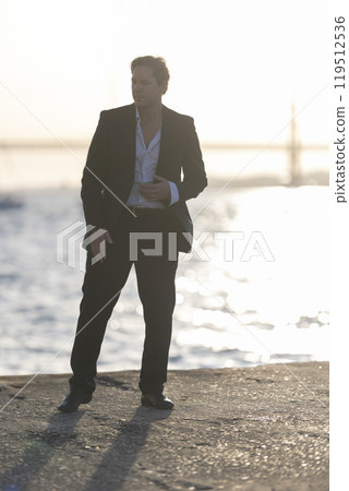 Elegant man dancing alone by the sea at sunset Elegant man dancing alone by the sea at sunset 119512536