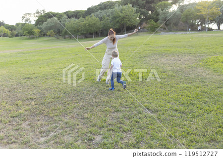 Mother and son playing tag in the park on a sunny day Mother and son playing tag in the park on a sunny day 119512727