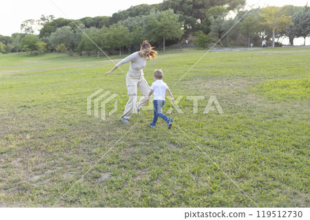 Mother and son playing tag in the park on a sunny day Mother and son playing tag in the park on a sunny day 119512730