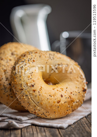 Bagel sprinkled with fried onion, sesame and poppy seeds on wooden table. 119513596