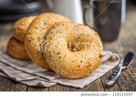 Bagel sprinkled with fried onion, sesame and poppy seeds on wooden table. Bagel sprinkled with fried onion, sesame and poppy seeds on wooden table. 119513597
