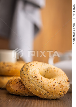 Bagel sprinkled with fried onion, sesame and poppy seeds on wooden table. 119513602