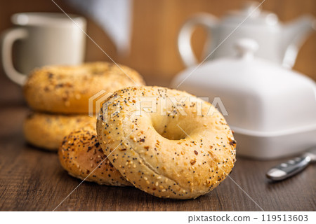 Bagel sprinkled with fried onion, sesame and poppy seeds on wooden table. 119513603