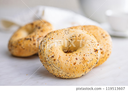 Bagel sprinkled with fried onion, sesame and poppy seeds on kitchen table. Bagel sprinkled with fried onion, sesame and poppy seeds on kitchen table. 119513607