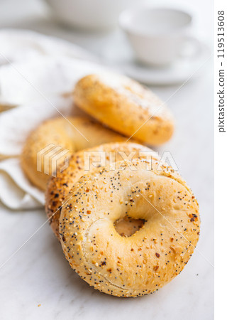 Bagel sprinkled with fried onion, sesame and poppy seeds on kitchen table. Bagel sprinkled with fried onion, sesame and poppy seeds on kitchen table. 119513608