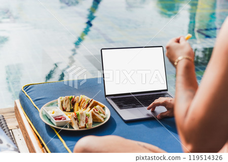 Man working on laptop on vacation eat club sandwich by the pool. Man working on laptop on vacation eat club sandwich by the pool. 119514326