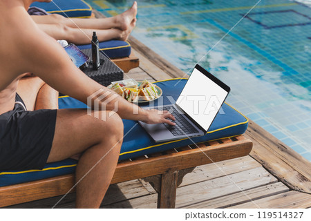 Man working on laptop on vacation eat club sandwich by the pool. Man working on laptop on vacation eat club sandwich by the pool. 119514327