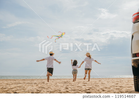 Asian family is flying a kite while running on the beach. Happy parents mother and father with their child playing with kite, The car is parked nearby, and the family is enjoying their time together Asian family is flying a kite while running on the beach. Happy parents mother and father with their child playing with kite, The car is parked nearby, and the family is enjoying their time together 119514607