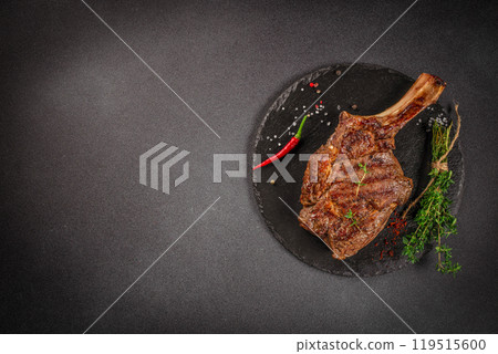 Tomahawk rib beef steak with spices and herbs on a dark background. top view. copy space for text 119515600