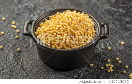 Raw ptitim pasta in a ceramic bowl on a dark background. top view 119515655
