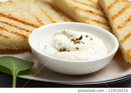 Cup with cheese sauce on the kitchen table. 119516250