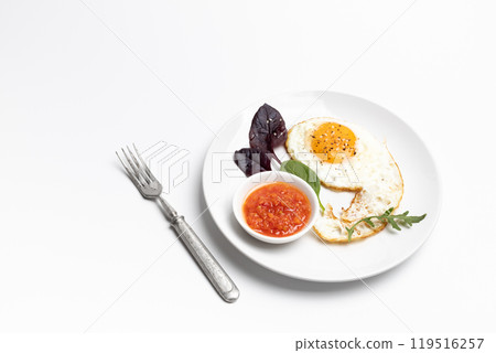 Fried egg and red sauce on the plate with the white background. Fried egg and red sauce on the plate with the white background. 119516257