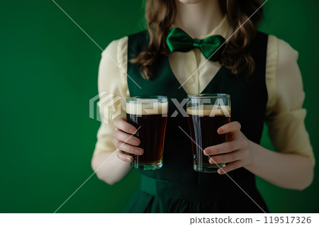 A person holding two glasses of dark beer wearing a green bow tie, set against a rich green A person holding two glasses of dark beer wearing a green bow tie, set against a rich green 119517326