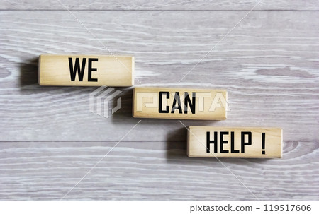 We can help with a message written on wooden blocks with a gray background. We can help with a message written on wooden blocks with a gray background. 119517606