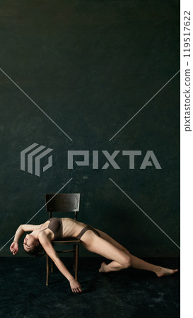 Poster. Beautiful woman drapes herself over chair, arms and legs extended, giving relaxed yet elegant feel in soft lighting. Copy space. 119517622