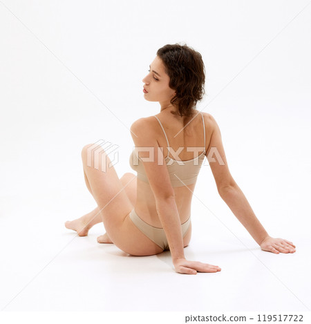 Rear view of model with healthy toned body and radiant skin reflect lifestyle focused on wellness, body care against white studio background. Rear view of model with healthy toned body and radiant skin reflect lifestyle focused on wellness, body care against white studio background. 119517722