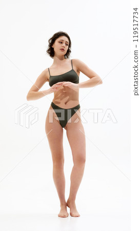 Full-length photo of young beautiful woman posing in lingerie looking away against white studio background. 119517734