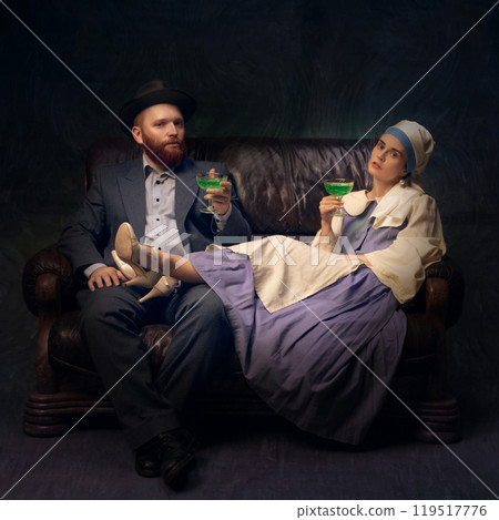 Vintage couple relaxing with drink. Man and woman relaxing on leather couch and drinking alcohol drinks 119517776