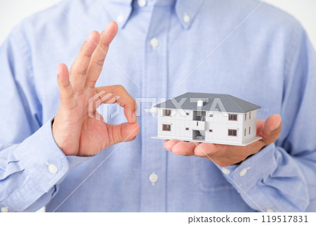 A middle-aged man making a circle sign while holding a model of an apartment building 119517831