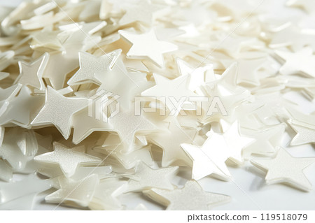 A close-up of shiny white star-shaped confetti scattered on a surface, perfect for celebrations and 119518079