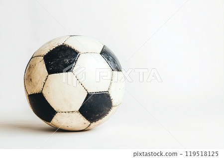 A classic black and white soccer ball resting on a light background, showcasing its worn surface and 119518125
