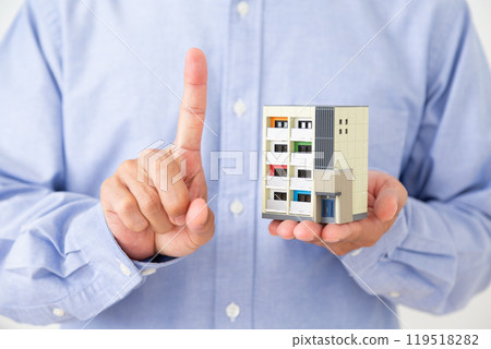 一名中年男子拿著公寓模型，舉起食指 119518282