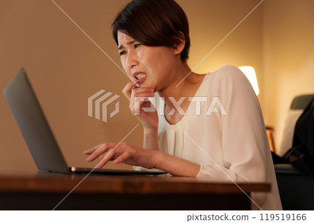 Overworked woman working on a computer at home at night Overworked woman working on a computer at home at night 119519166