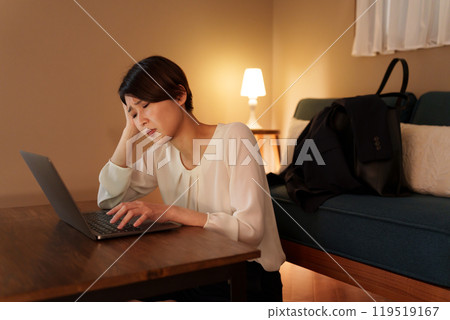 Overworked woman working on a computer at home at night Overworked woman working on a computer at home at night 119519167