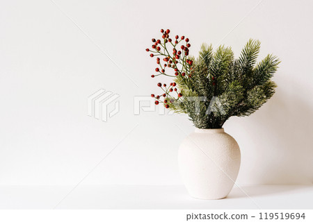 Minimalistic Christmas composition with fir branches in ceramic vase on white background Minimalistic Christmas composition with fir branches in ceramic vase on white background 119519694