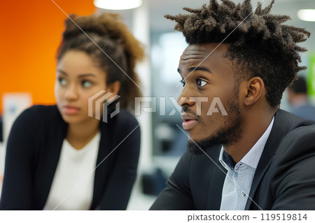 Two young professionals engaged in a discussion during a business meeting at a modern office setting Two young professionals engaged in a discussion during a business meeting at a modern office setting 119519814
