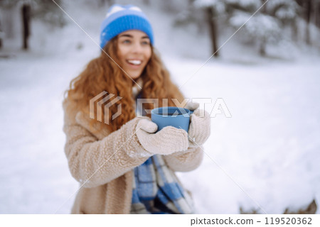 Young woman drinking a hot drink outdoors. Adventure concept. Lifestyle. 119520362