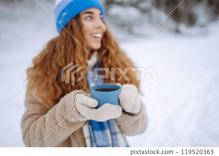 Young woman drinking a hot drink outdoors. Adventure concept. Lifestyle. 119520363