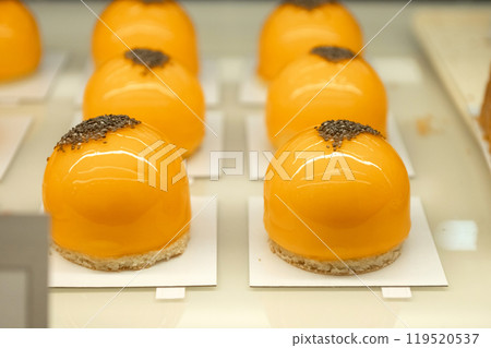 Orange dome-shaped pastries with glossy glaze and chia seeds on top. Gourmet dessert food photography Orange dome-shaped pastries with glossy glaze and chia seeds on top. Gourmet dessert food photography 119520537