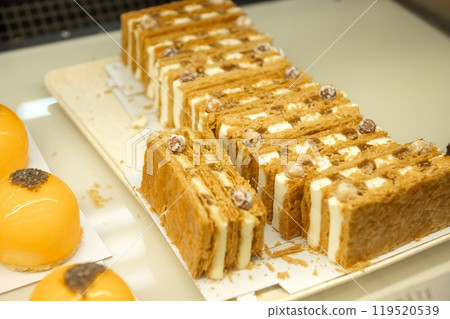 Layered mille-feuille pastries with cream and hazelnuts on display. Close-up bakery food photography 119520539